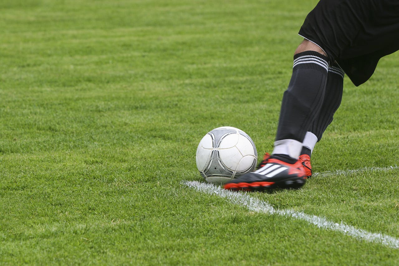 portfolio-03 Dynamic shot of a soccer player kicking the ball on a grassy field, showcasing fast-paced sports action.