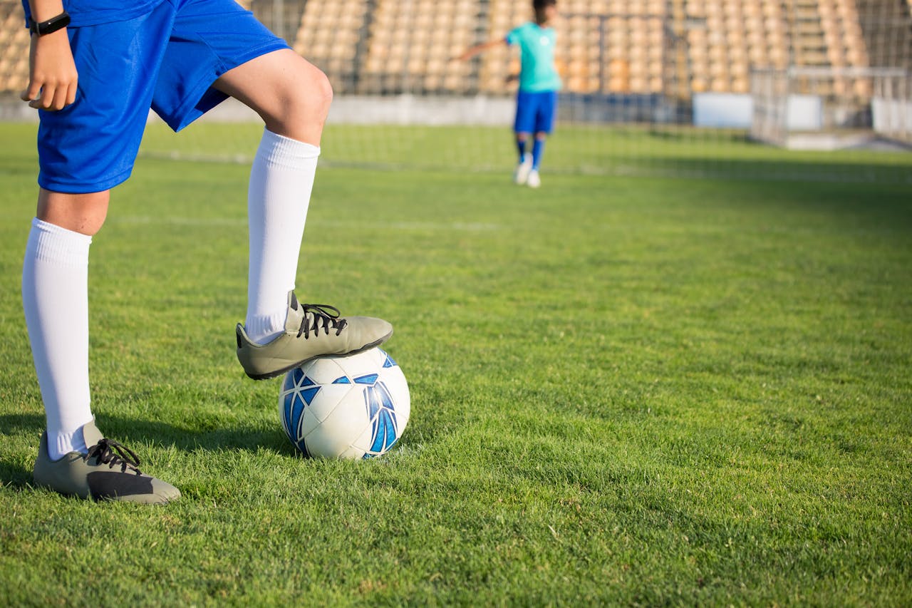 our-mission Young soccer player in blue uniform training on a sunny day at a football field in Portugal.