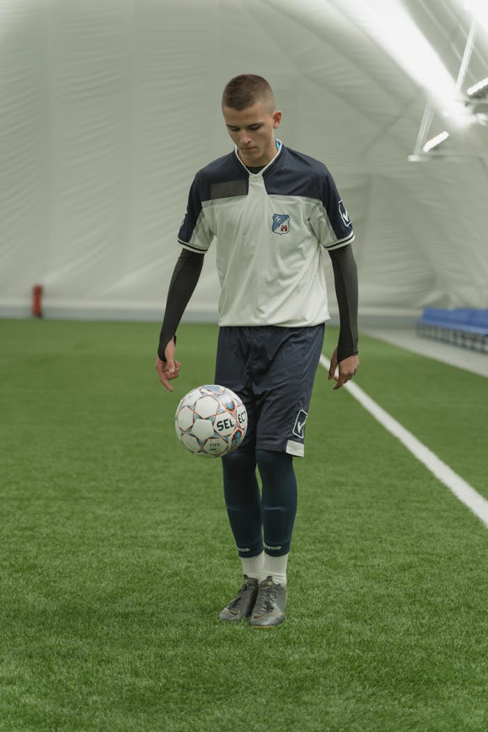 why-choose-us Focused young soccer player practicing ball control indoors. Perfect for sports training themes.